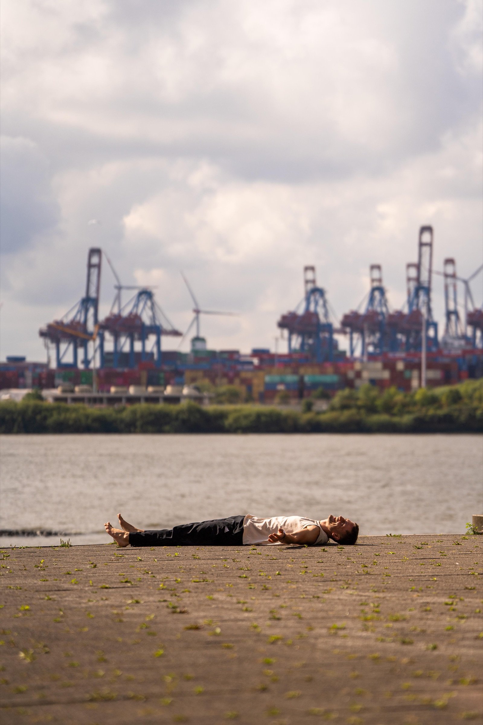 Lennart lying in savasana beside the Hamburg harbour